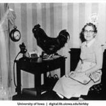 Florence Falk and rooster at table in dining room where Farmer's Wife broadcast originated, Shenandoah, Iowa, 1950s